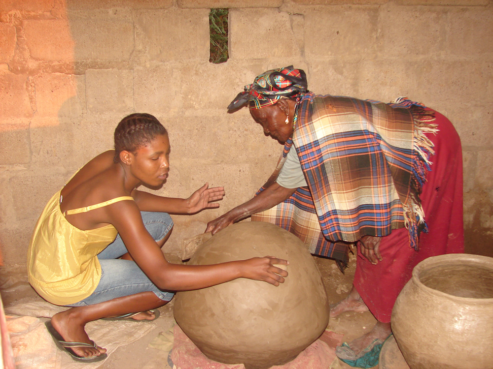 The Pot Master, Mmasekgwa Motlhware, instructing her granddaughter, Tumediso Motene on the smoothening of the pot
