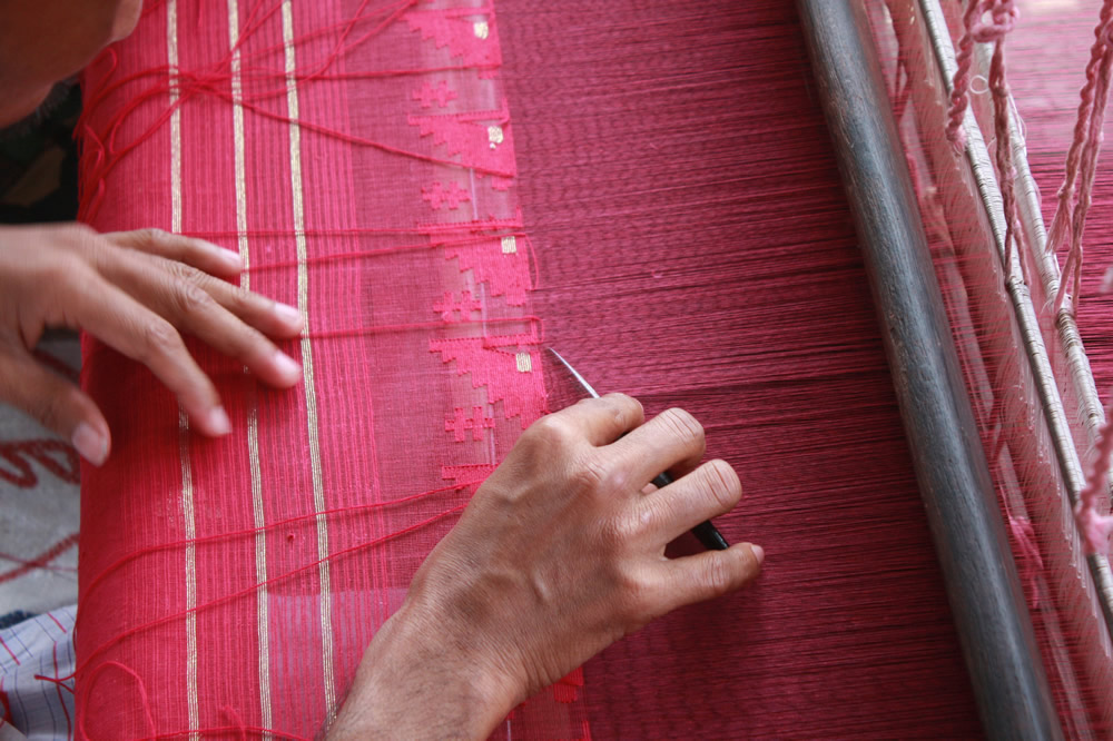 A weaver is seen using the kandu, an essential tool for weaving designs