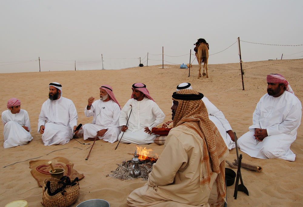 Three generations of Emirati Bedouins chanting Al-Taghrooda while having traditional coffee around a campfire at a camel farm 10 km away from Zayed City, Western Region, Abu Dhabi Emirate.