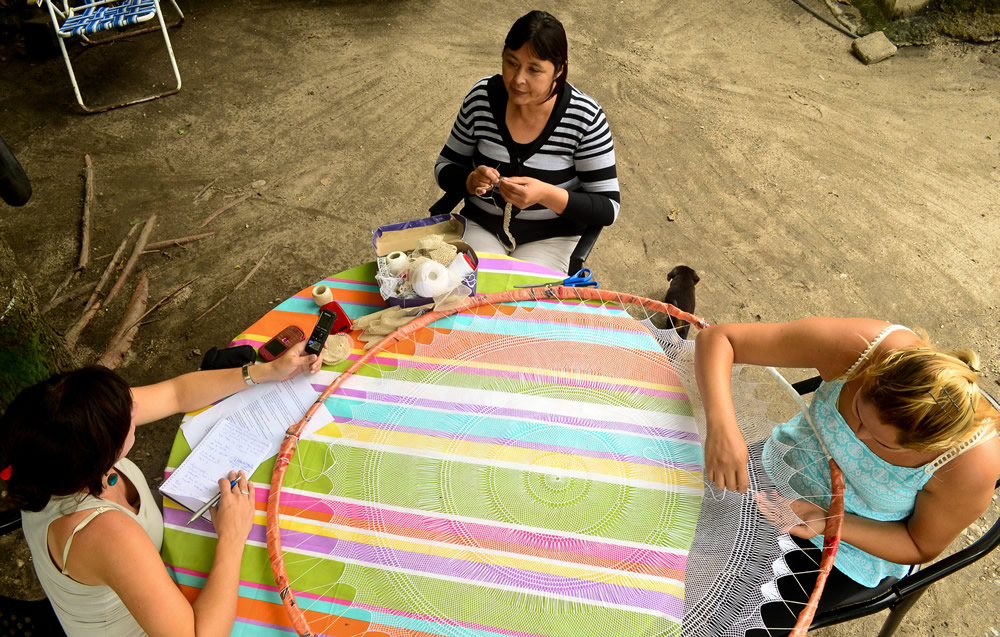 Claudia Aybar with her daughter, weaving in their yard during an interview