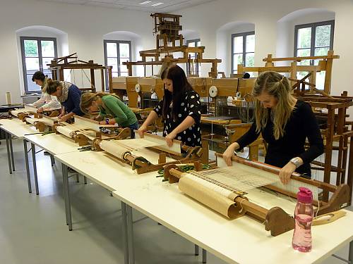 Students working on table-looms in the hand weaving studio of the Textile Center Haslach, creating seat pads out of waste materials