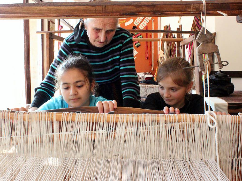 Stefka Zasheva is teaching her great-grandchildren Persiyana and Alex to weave on a loom - a traditional device for producing carpets and rugs