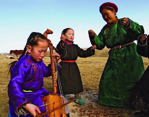 Children take part in a traditional song using Morin khuur (two-stringed fiddle) Mongolia 