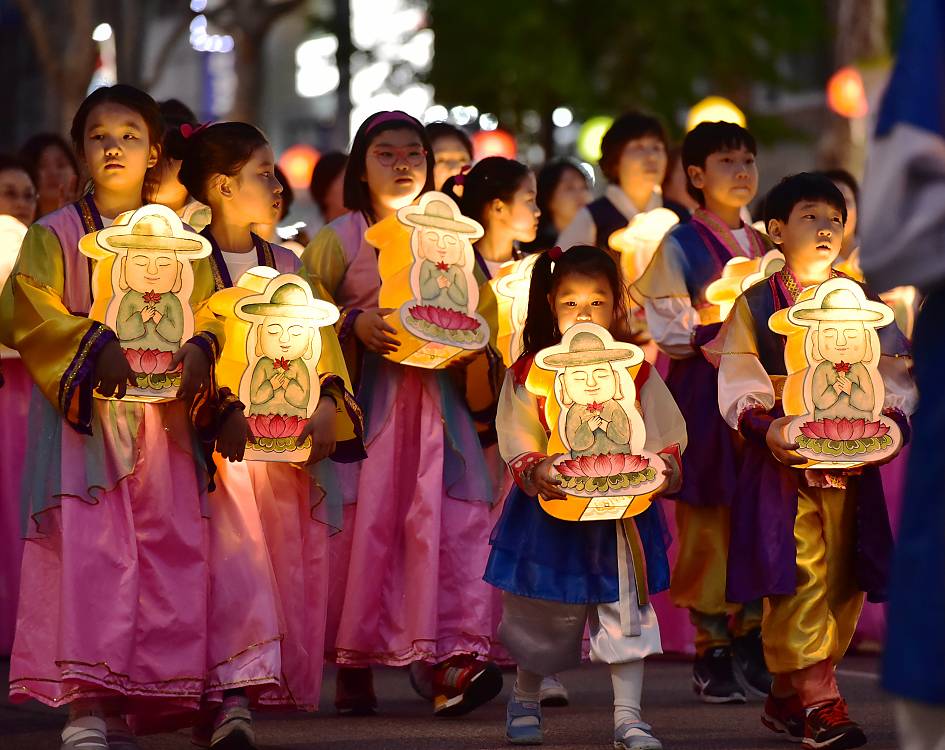 Children are parading with holding buddha-shaped lanterns