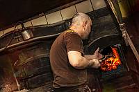 Baker adding wood to the wood-fired artisan oven.  Wood used is to be in it’s natural state as possible
