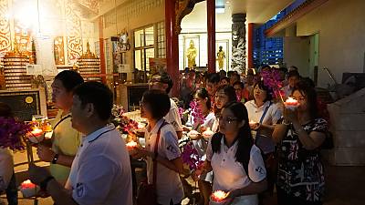 Buddhist devotees holding lighted candles at a temple as part of a procession on Vesak Day prior to COVID-19.