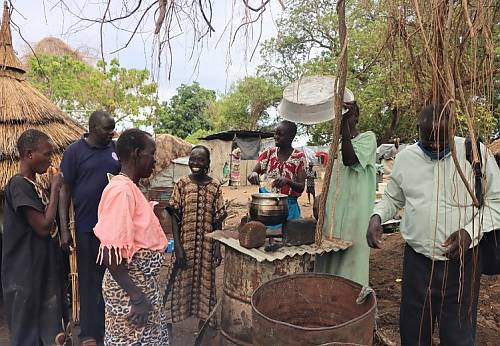 Un grupo de mujeres muestra cómo cocinan utilizando barriles y cubetas o cubos metálicos durante una inundación en Sudán del Sur