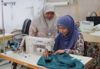 An instructor teaches her student how to sew a kebaya