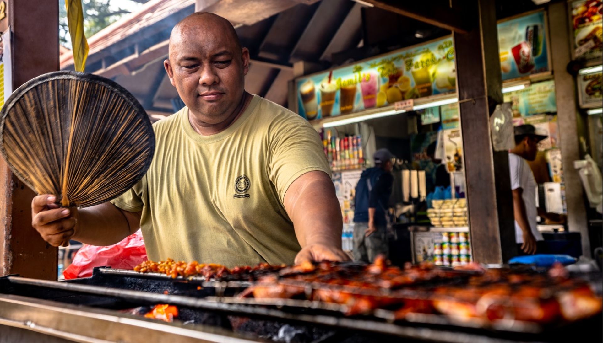 A Malay hawker prepares satay (seasoned and skewered meat grilled over hot charcoal)