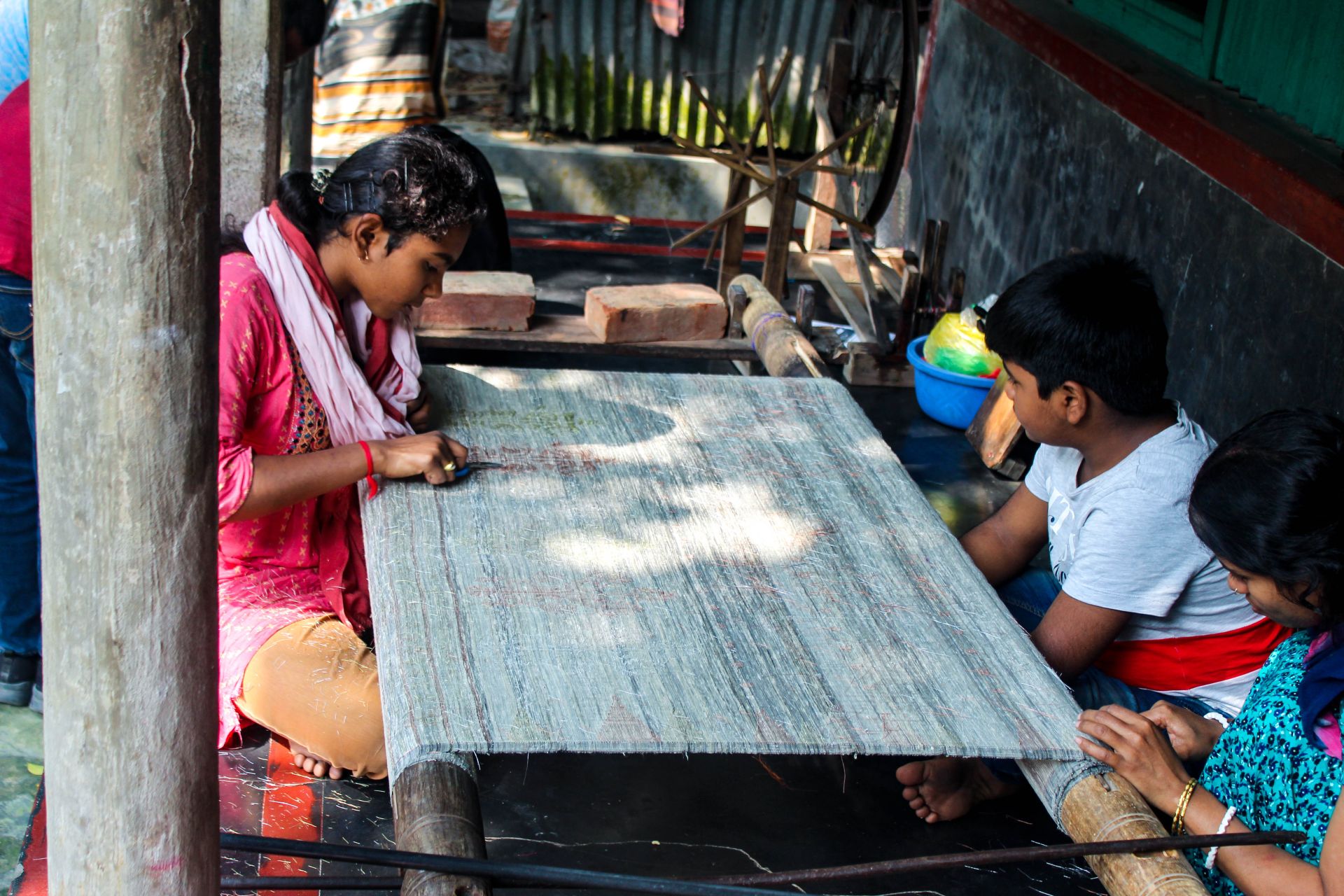 In addition to family members, children also play a significant role in saree weaving. This helps to pass down the skill to future generations. After the saree is woven, any excess thread from the design is cut and removed.