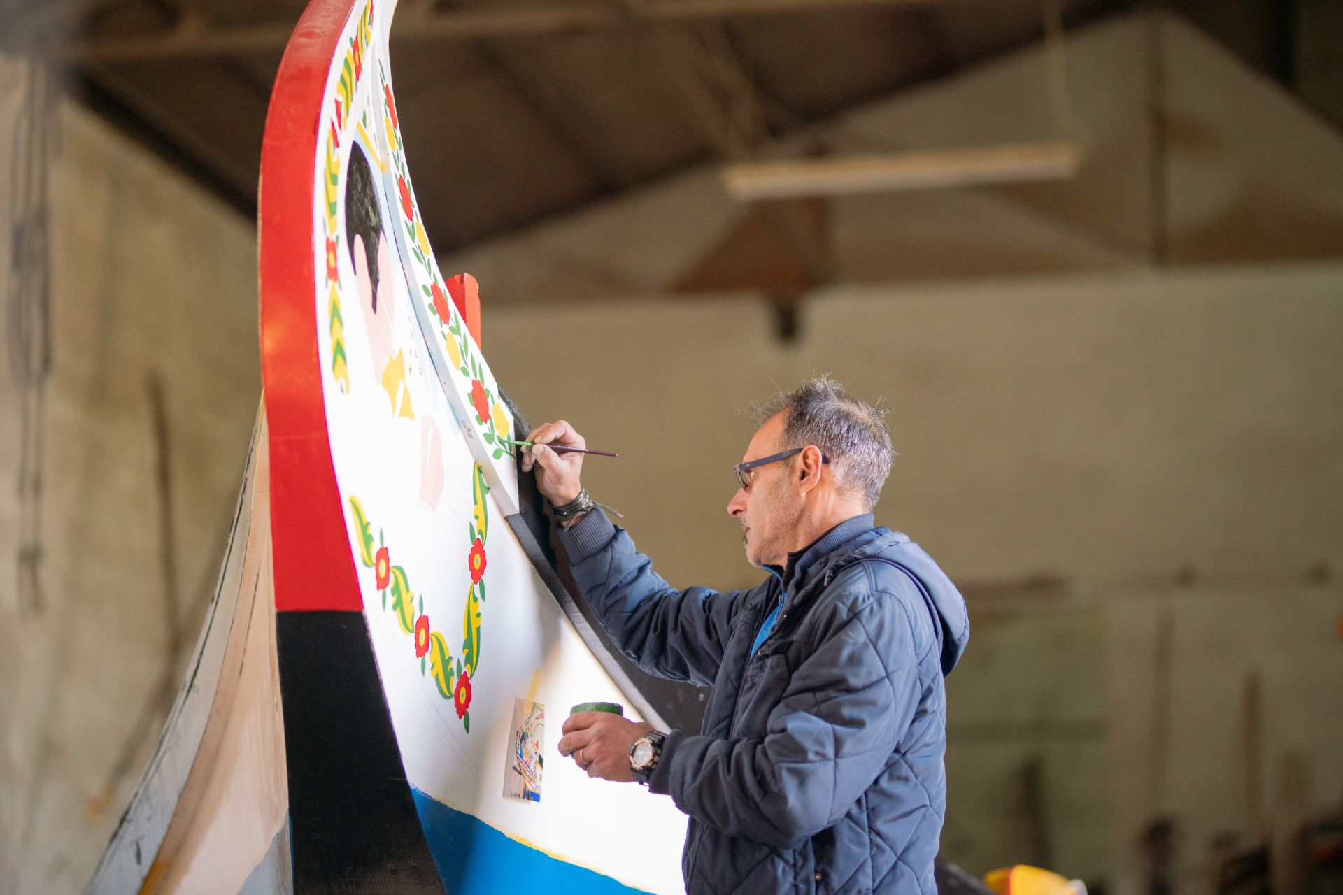 José Oliveira, the only painter from the Aveiro Region in activity, painting one of the bow panels of the Moliceiro Boat. The decoration of the boat consists of two bow panels and two stern panels