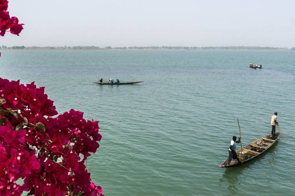 Two men in traditional boats on the Niger river in Segou, Mali